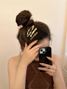 Three-piece hair clip set with marble acetate and gold waves worn on hair side