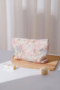 Close-up of pink embossed floral texture fabric and brand label on a makeup bag