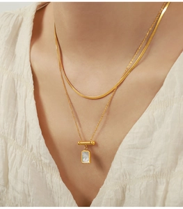 Detail of 18K gold-plated double-layer necklace with white shell pendant on model