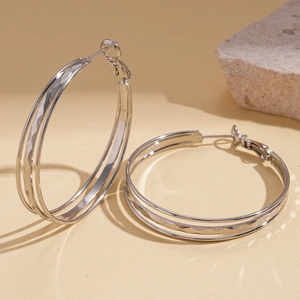 Detailed view of silver hoop earrings featuring triple layers and diamond-cut texture