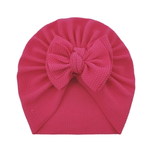 Gorro para bebé rosa oscuro con textura de gofre y un gran lazo decorativo