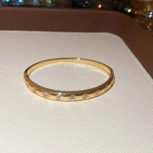 Gros plan d'un bracelet doré orné de zircons en forme de cœur sur cuir blanc