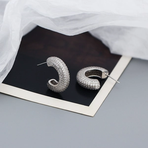 Detailed view of silver C-shaped earrings with micro-pave cubic zirconia on a minimalist card