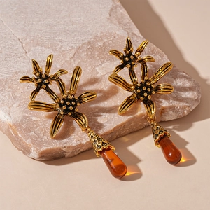 Vintage gold flower earrings with amber water drop pendants on a light stone base