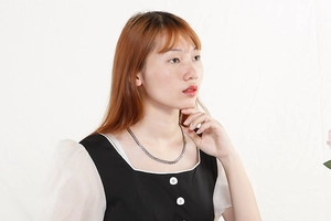 Gros plan d'un collier cœur argenté porté par un mannequin avec une chaîne classique