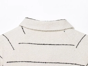 Dettaglio del tessuto tweed beige con cuciture a contrasto nere su colletto e spalla