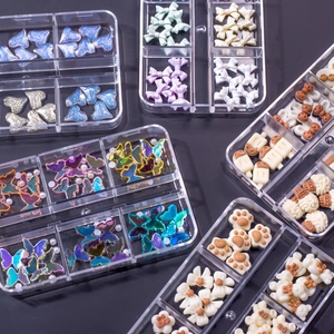 Macro view of assorted resin nail art charms including bows and bears in a storage box