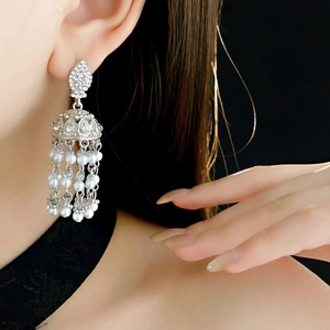 Macro detail of vintage silver tassel earrings with white pearls and sparkling rhinestones