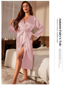 Detail of pink satin long-sleeve bathrobe with V-neckline and matching belt in bedroom
