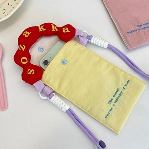 Détail d'un sac pour téléphone en toile jaune vif avec broderie et bandoulière en corde violette
