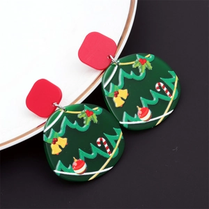Détail de boucles d'oreilles sapin de Noël en acrylique sur une assiette blanche