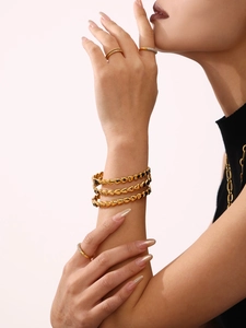 Detail view of 18K gold plated heart chain bracelet and matching rings worn by a model