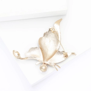 Detail view of the gold alloy butterfly brooch back with pin clasp and pearl accent