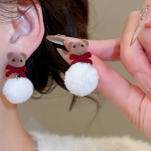 Close-up of brown flocked teddy bear earrings with white pompom and red bow detail