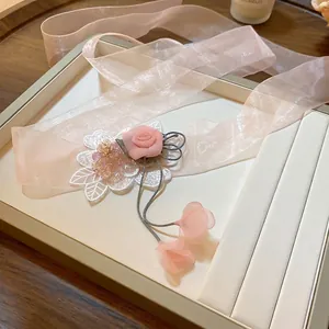Pink fabric rose choker necklace with long organza ribbon and lace details on display