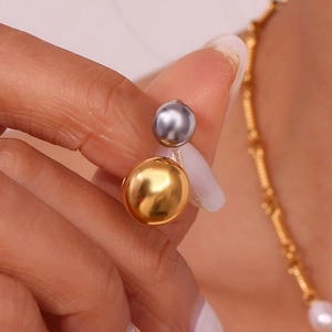 Gold and silver double bead open ring in stainless steel held between fingers