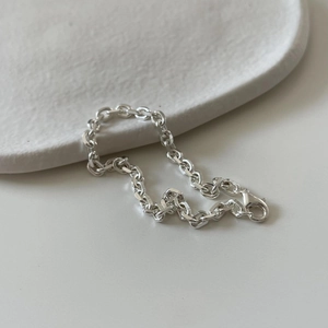 Detail of 925 sterling silver chain bracelet with lobster clasp on a ceramic tray
