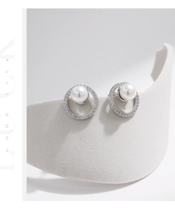 Macro detail of S925 silver pearl stud earrings with sparkling crystal halo setting