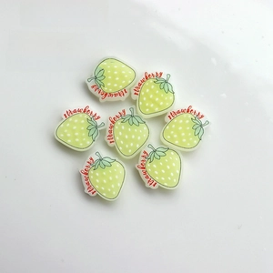 Flat lay detail of seven light green resin strawberry charms for DIY crafts and decor
