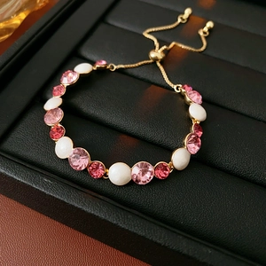 Détail du bracelet doré ajustable avec cristaux roses et perles blanches en boîte