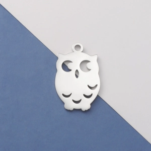 Close-up of a silver owl-shaped pendant with hollow design on blue and white background