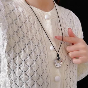 Irregular geometric lava-style metal pendant with black cord necklace on model