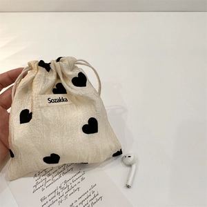 Detail of cream drawstring pouch with heart patterns holding small electronic gadgets