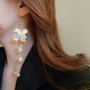 Close-up of elegant long tassel flower earrings with silver metallic petals on model