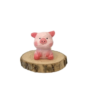 Figurine de cochon en bois rose sculptée à la main sur un support en bois naturel