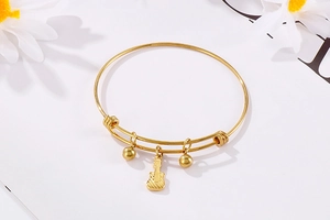 Detail of adjustable gold guitar charm bracelet with beads on white floral background