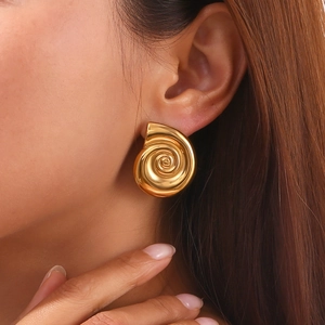 Macro shot of 18K gold plated spiral snail shell earrings with a polished glossy finish