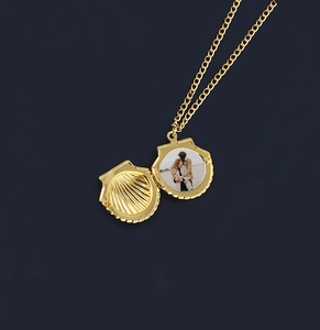 Golden shell locket necklace with open photo compartment on deep blue background