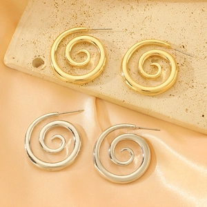 Polished gold and silver spiral heart earrings on travertine and silk background