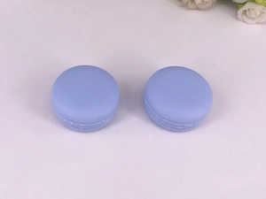Detail view of two lavender macaron-shaped cosmetic jars on a white floral background