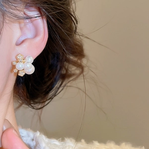 Vue latérale macro d'élégantes boucles d'oreilles fleuries en perles et zircons dorés