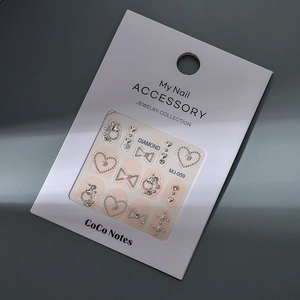 Detail of silver bow and heart nail art charms with pearls on display card