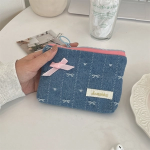 Dettaglio del portamonete in denim ricamato con fiocco rosa e motivi a cuore