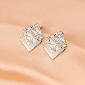 Macro detail of silver square stud earrings with textured and polished layered metal