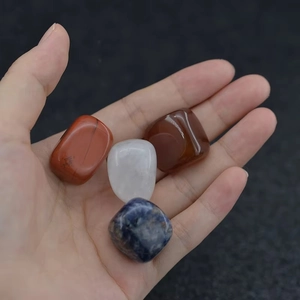 Polished chakra stones including red jasper and quartz being held in hand for size
