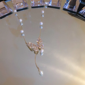 Gold-plated butterfly necklace with freshwater pearls and zircon on reflective surface