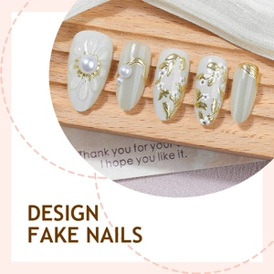 Faux ongles amande verts avec relief doré et perles sur un présentoir en bois