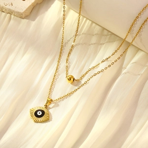 Gold double layer necklace with evil eye pendant and gold bead on beige fabric