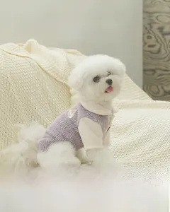 Detail of soft purple plush dog sweater with bear patch on a fluffy white blanket