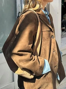 Détail d'une veste en daim marron avec revers et grand sac à bandoulière assorti