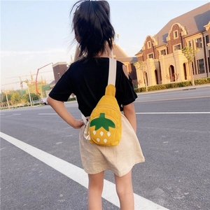 Outdoor view of child wearing a yellow strawberry canvas crossbody chest bag for kids