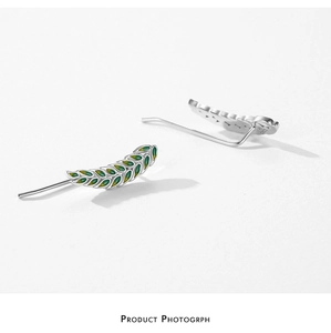 Detail of silver leaf earrings with green enamel finish on a clean white background