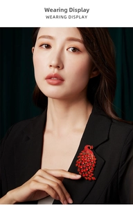 Detailed view of a sparkling red crystal peacock brooch on a black formal blazer lapel