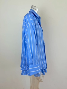 Detail of oversized blue striped cotton shirt featuring wide cuffs and classic collar