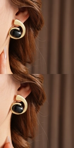 Close-up of vintage gold geometric earrings with black oval stones worn by a model