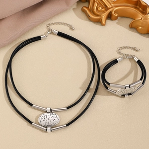 Set di gioielli in cordoncino nero con pendenti ovali in argento martellato e dettagli